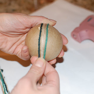Teal yarn being wrapped around a foam craft ball