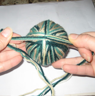 Yarn strands crossed around the bottom of a yarn ball ornament