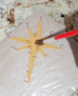 Applying fabric stiffener to a gold crochet Star of Bethlehem