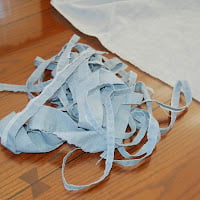 Trimming the sewn edges from an old bedsheet before making fabric yarn