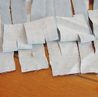 Cutting alternating fabric strips through the top and bottom layers of a folded bedsheet