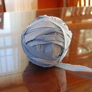 Rolling a continuous strip of fabric from an old bedsheet into a ball of yarn