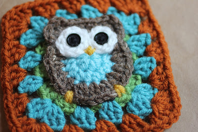 Yellow yarn embroidered to form the crochet owl&rsquo;s beak and feet
