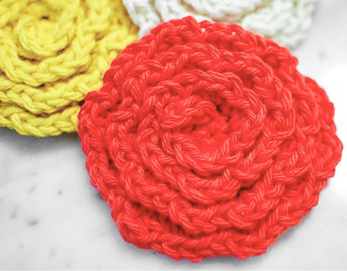 Close-up of a crochet flower facial scrubbie showing the petal stitches