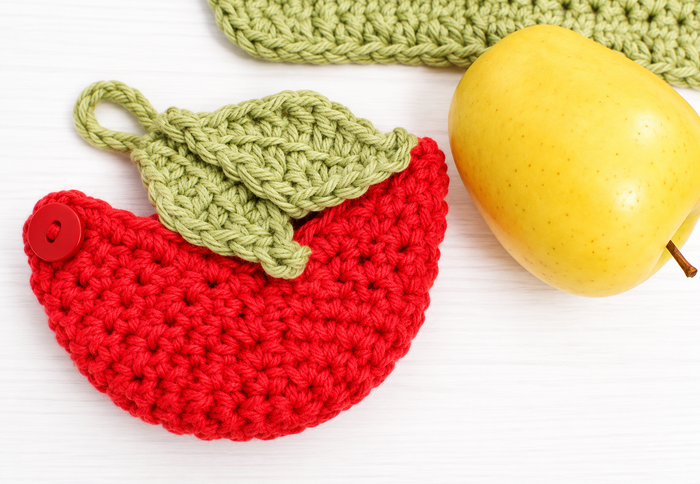 Crochet apple cozy opened to show leaf button closure