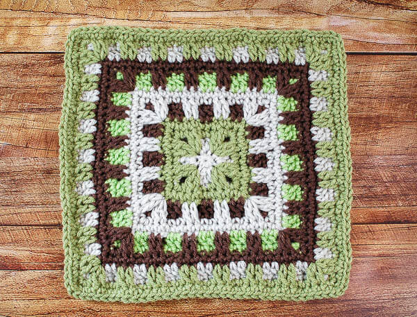 Close-up of a brown, green, and cream Caterpillar stitch crochet square