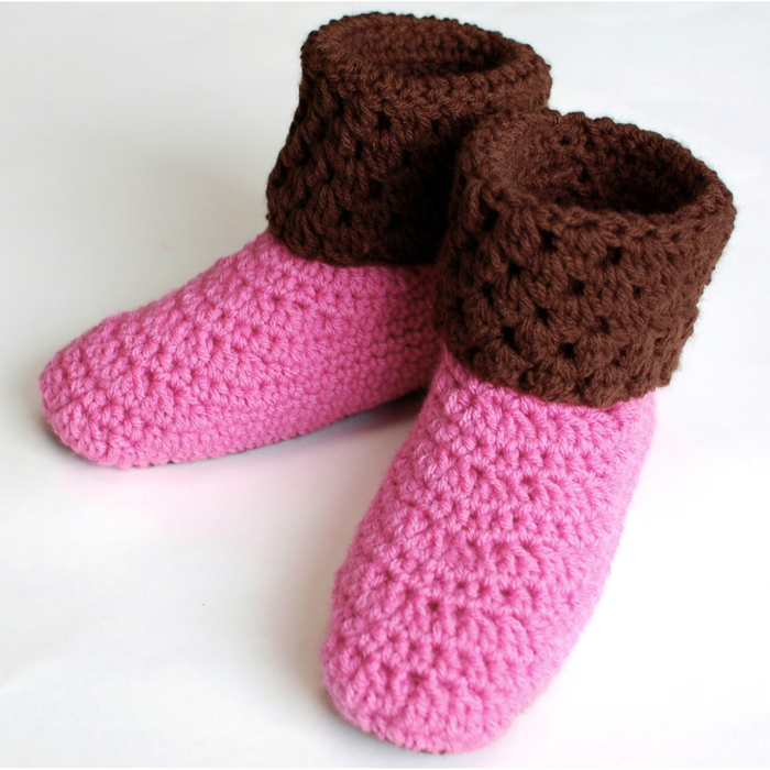 Pair of pink crochet bootie slippers with brown textured ankle cuffs, viewed from the front and side.